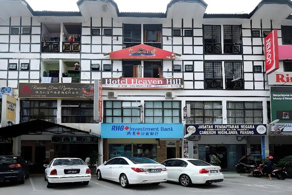 Un immeuble à plusieurs étages, sur lequel on peut lire les enseignes « Hotel Heaven Hill », « Banque d’investissement » et « Cameron Highlands, Pahang ».