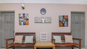 Ein Zimmer mit zwei hölzernen Bänken, einem kleinen Tisch und drei Kunstwerken an der Wand.