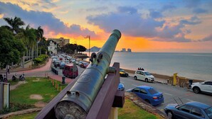 A cannon on display with a view of the sunset over the ocean. - Feringghi Stay Iinn (George Town)