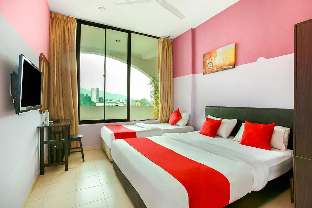 A hotel room with two beds, a TV, a small table, and a window with a view of buildings.