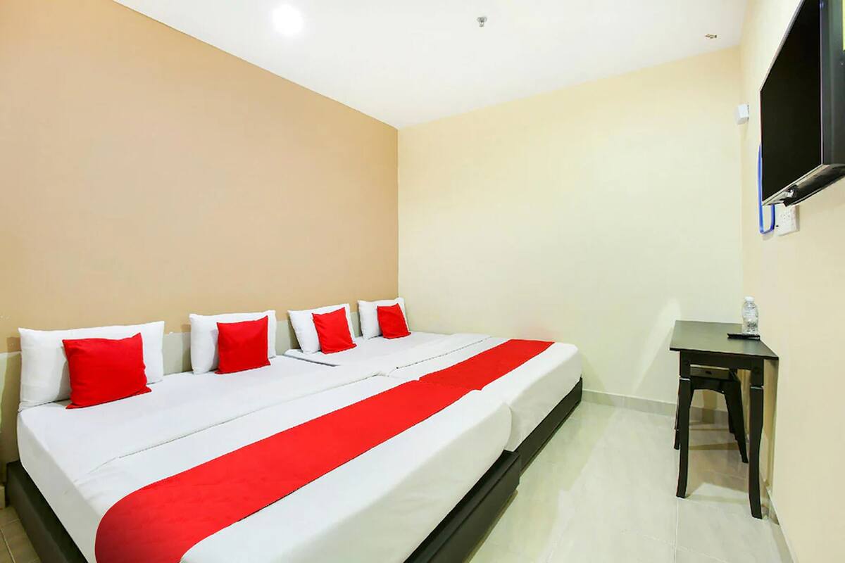 A hotel room with a bed, a desk, and a TV mounted on the wall.