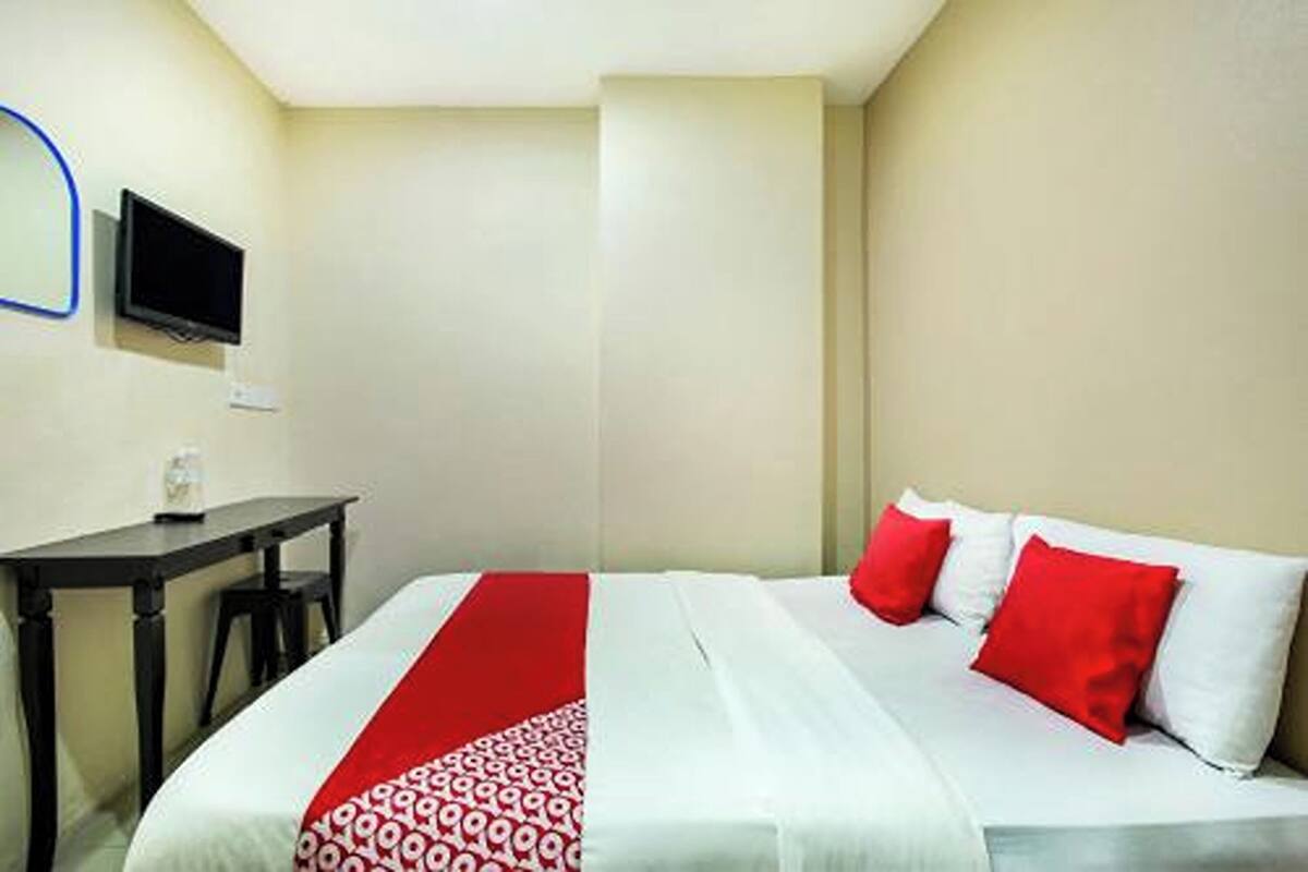 A hotel room with a bed, a desk, and a television.