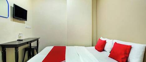 A hotel room with a bed, a desk, and a television.