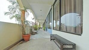 A covered balcony with potted plants, a bench, and a view of the sky. - Feringghi Stay Iinn (George Town)