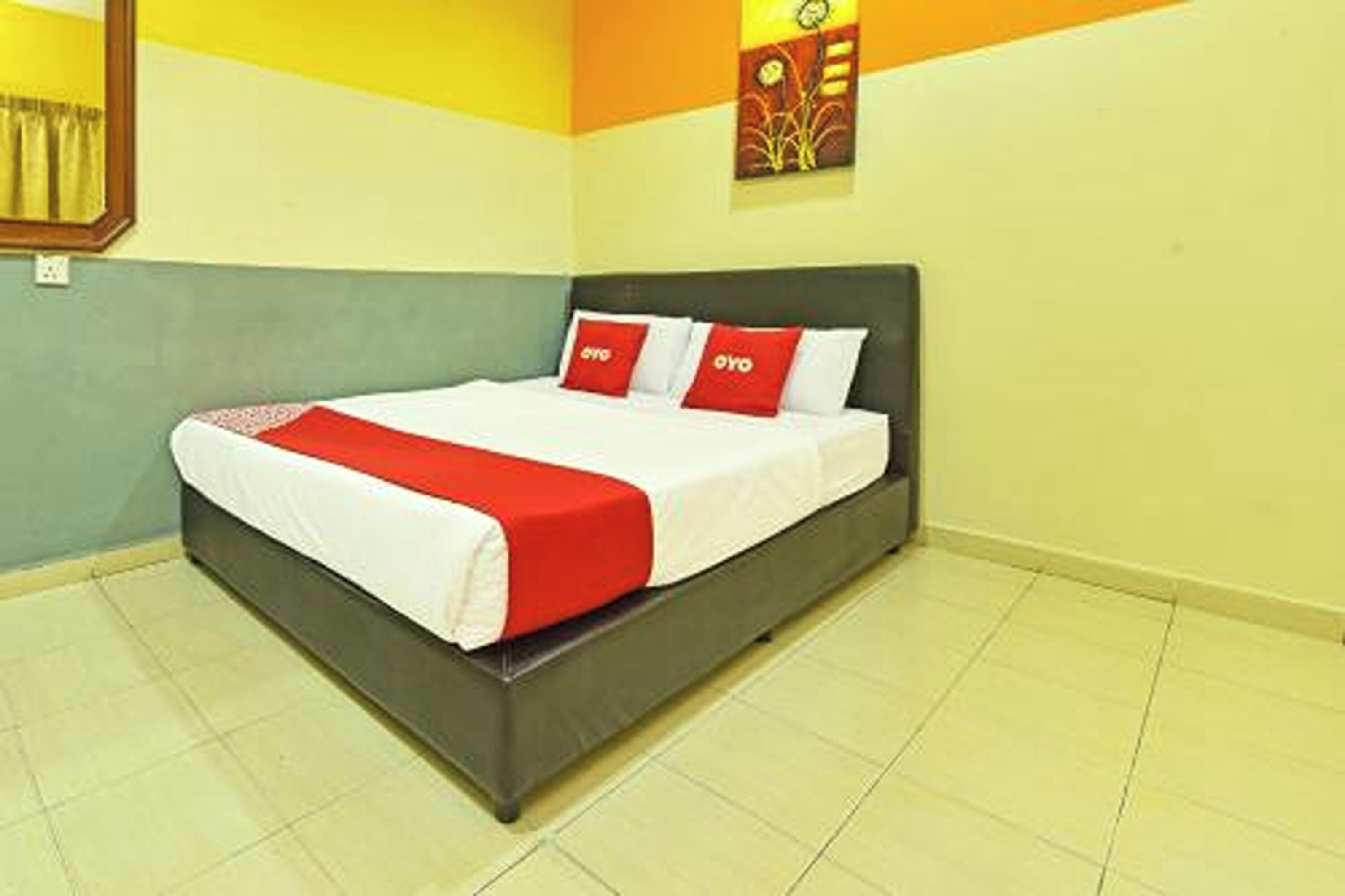 A bed with a white and red bedspread, a dark headboard, and two red pillows with white text.
