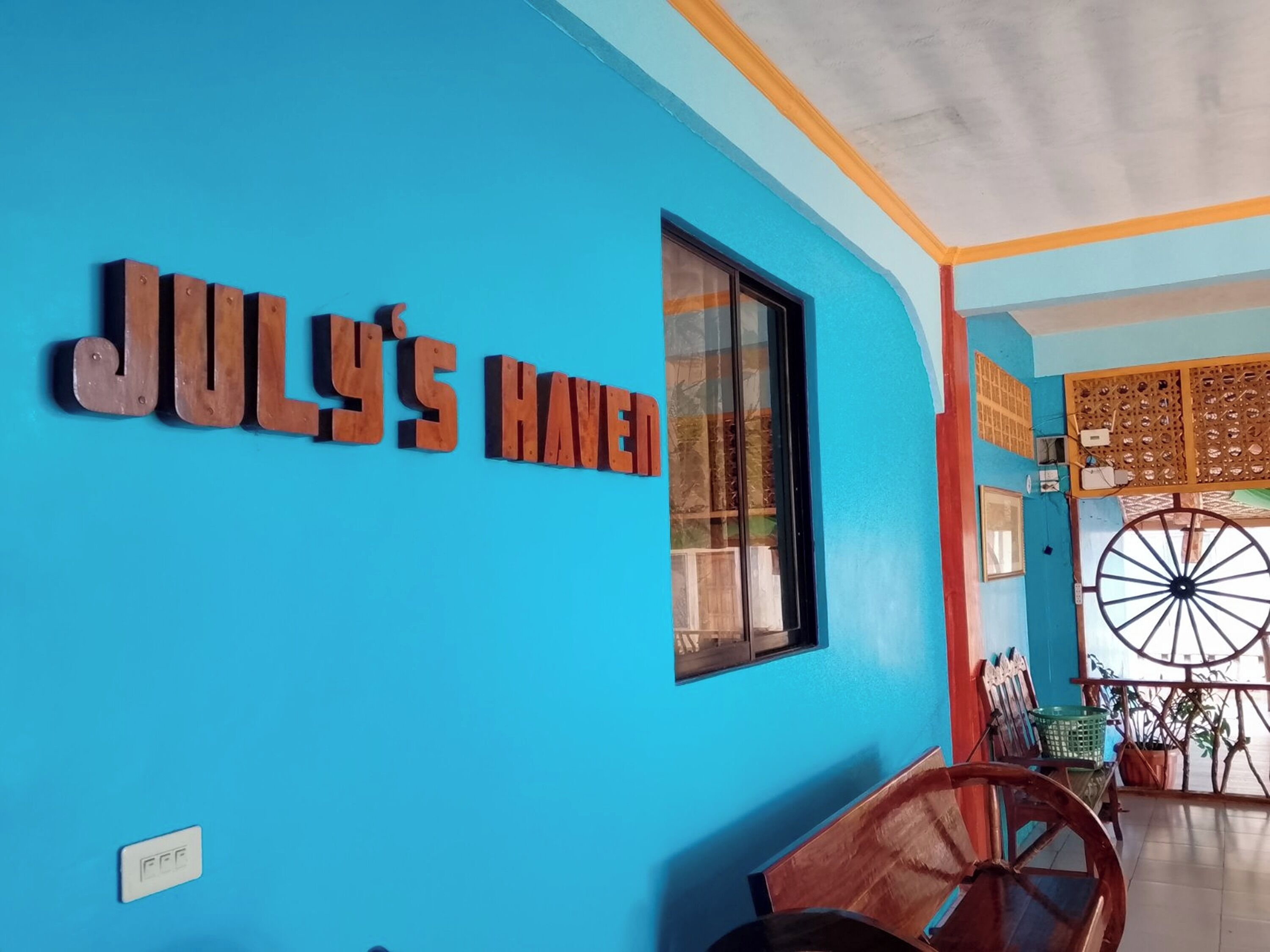 Une pièce avec un mur bleu et une enseigne en bois sur laquelle on peut lire : « JULY'S HAVED ».
