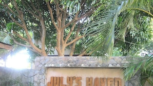 A stone wall with the text "JULY'S HAVEN" and a tree behind it.