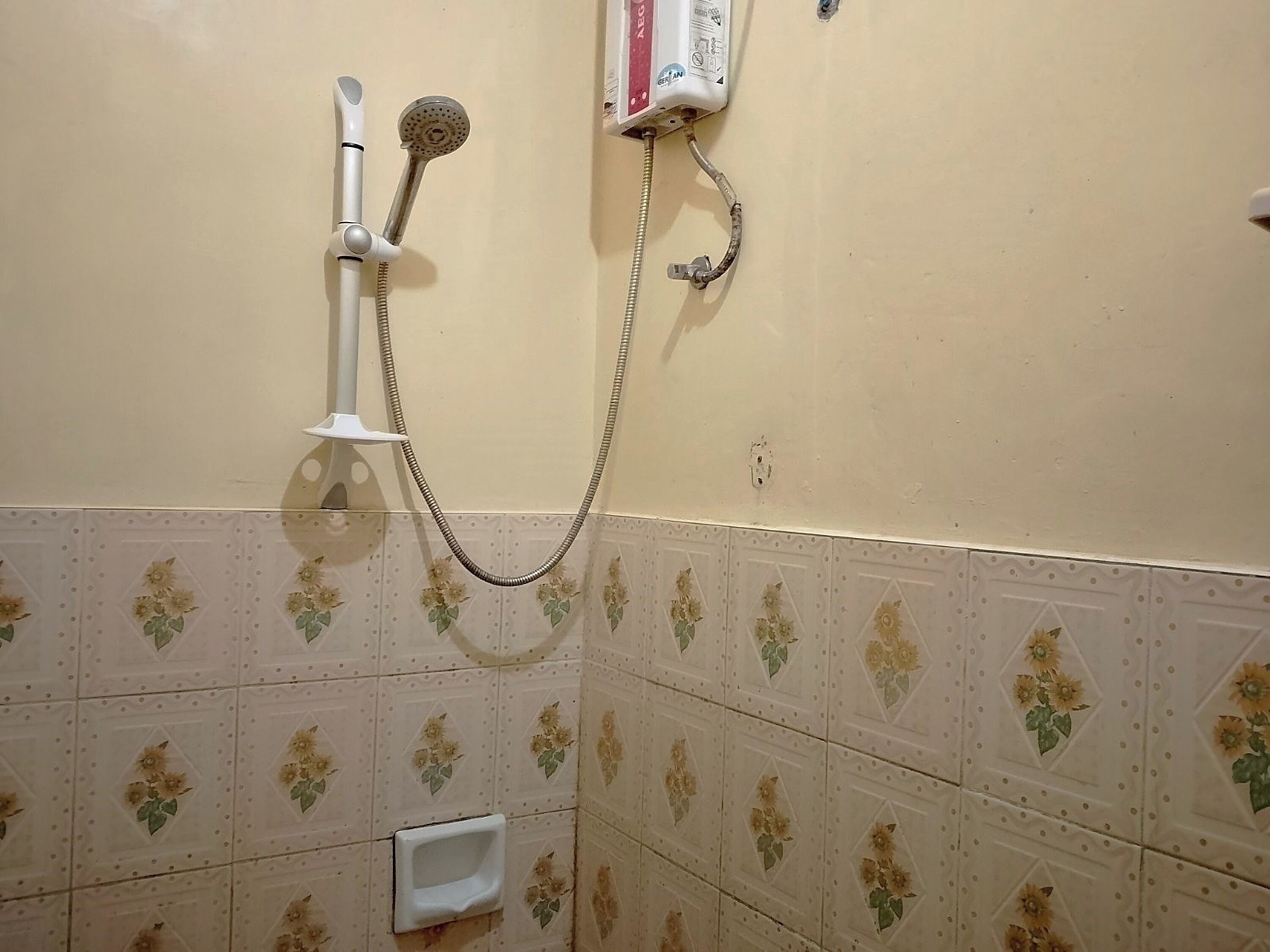 Un bagno con doccia, asciugamano elettrico e termosifone a parete.