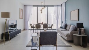 Een moderne woonkamer met een bank, een eettafel, stoelen, een televisie en een lamp.