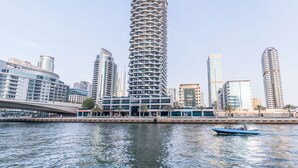 A modern high-rise building with a unique spiral design, surrounded by other contemporary buildings and a waterfront.