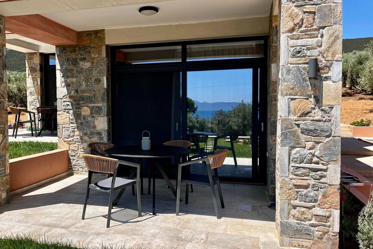 A stone-clad patio with outdoor seating and a view of the sea.