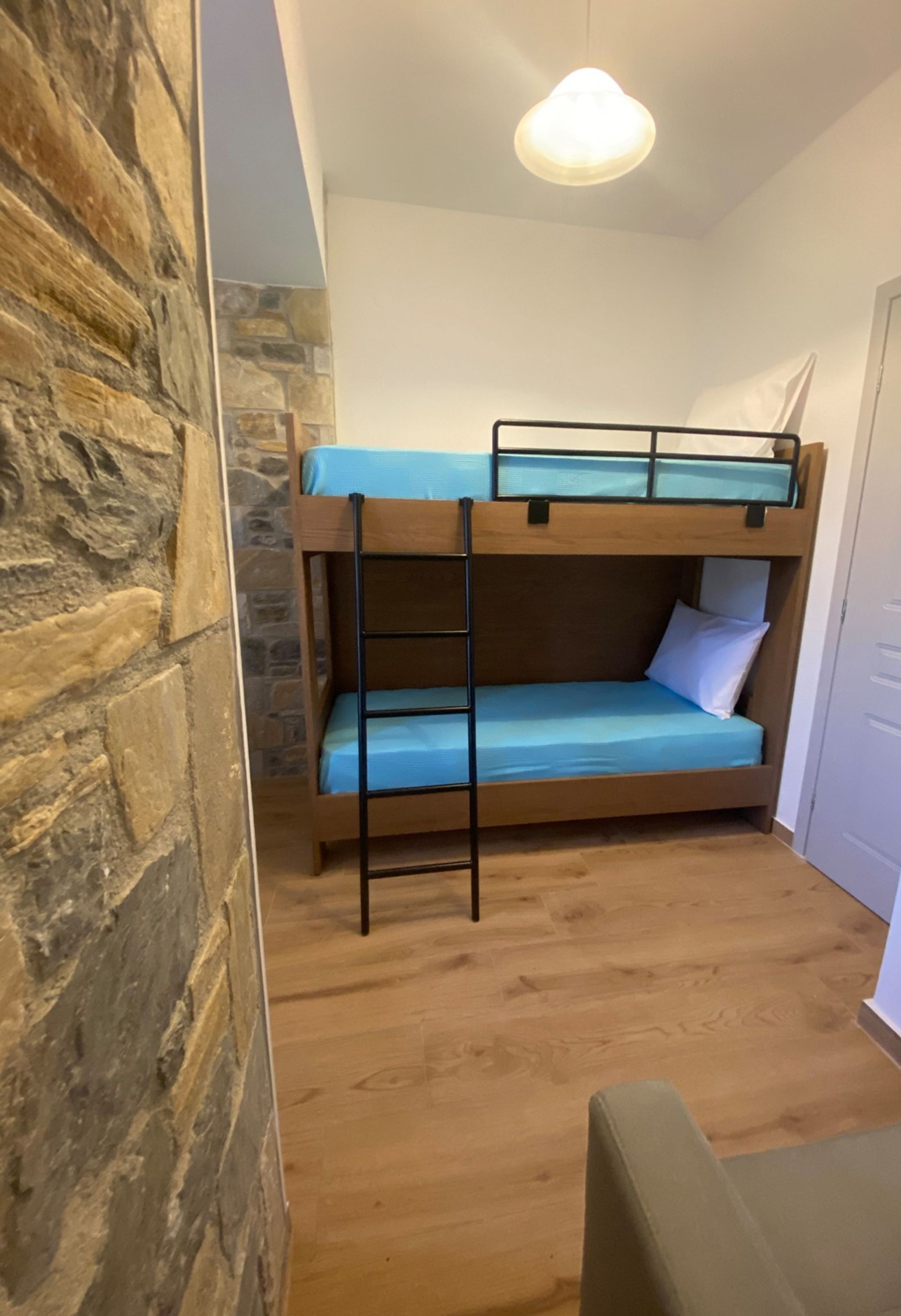 Ein Stockbett mit einer Leiter, einer Steinwand und einem Holzboden.
