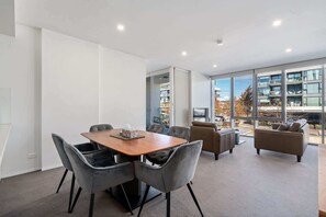 A modern interior with a wooden table, grey upholstered chairs, and a sofa. - Spacious Lakefront Apartment with Pool Access (Kingston)