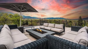 A patio with outdoor furniture, a fire pit, and a view of mountains.