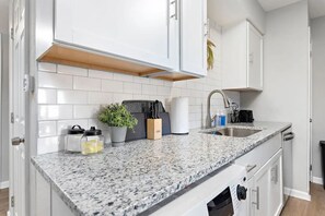 A modern kitchen with white cabinets, granite countertops, and a stainless steel sink.