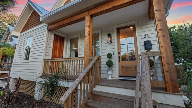 Une maison à deux étages avec un porche en bois, une porte d’entrée et une boîte aux lettres.