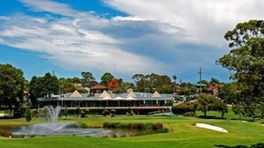 Un parcours de golf doté d’un club-house, d’un étang et d’une fontaine.