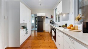 Une cuisine moderne avec des meubles blancs, un réfrigérateur en acier inoxydable et un plancher en bois.