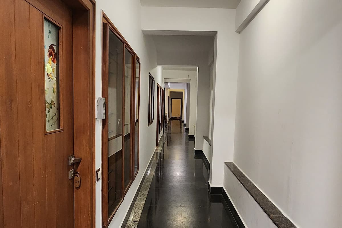 A long, narrow hallway with wooden doors on one side and a black tiled floor.