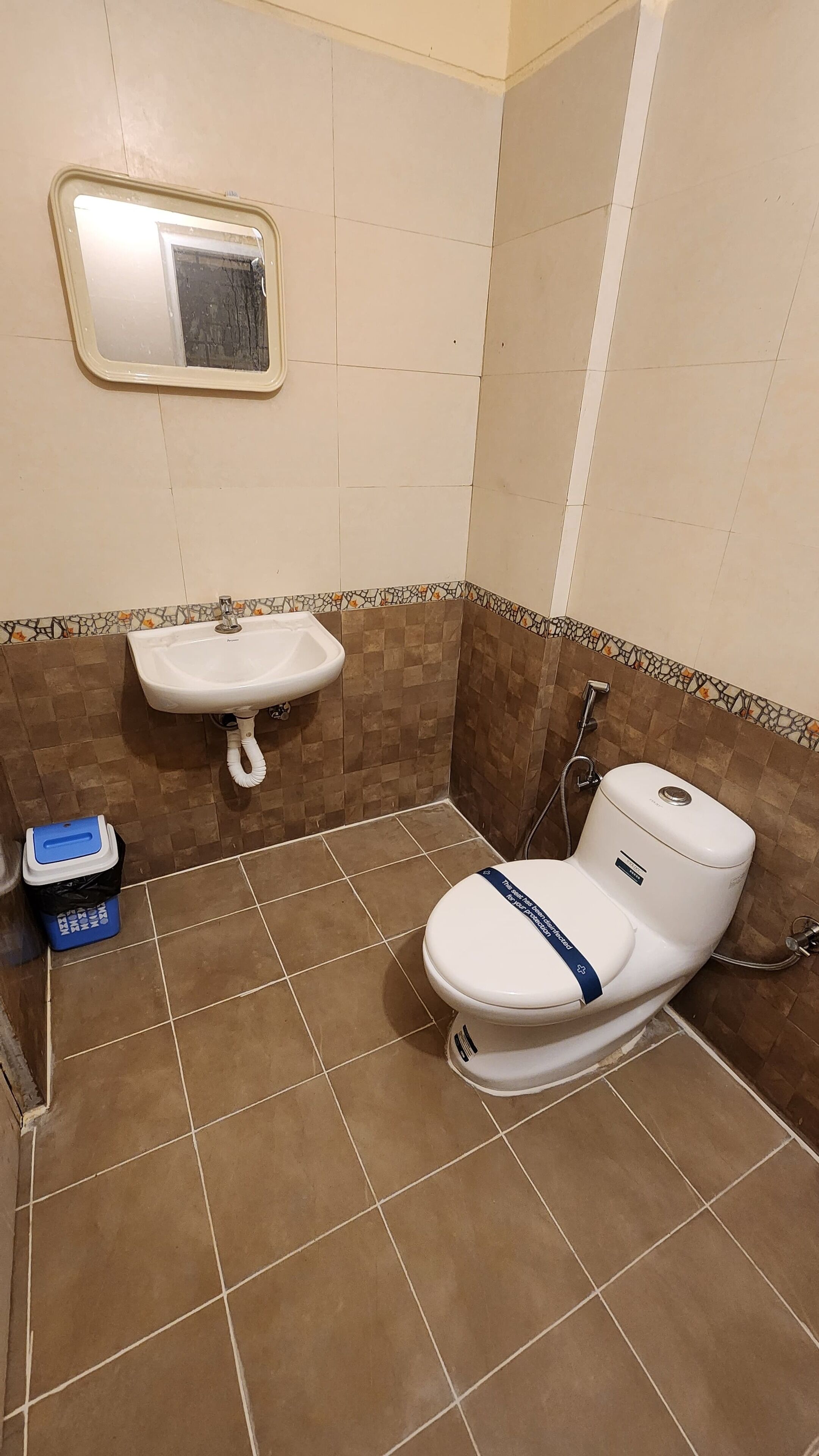 A bathroom with a white toilet, a sink, and a small trash bin.