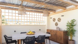 A dining area with a table, chairs, a potted plant, and a view through a window. - Old Town Charm – Cozy 2BR with Rooftop Terrace (Rethymno)