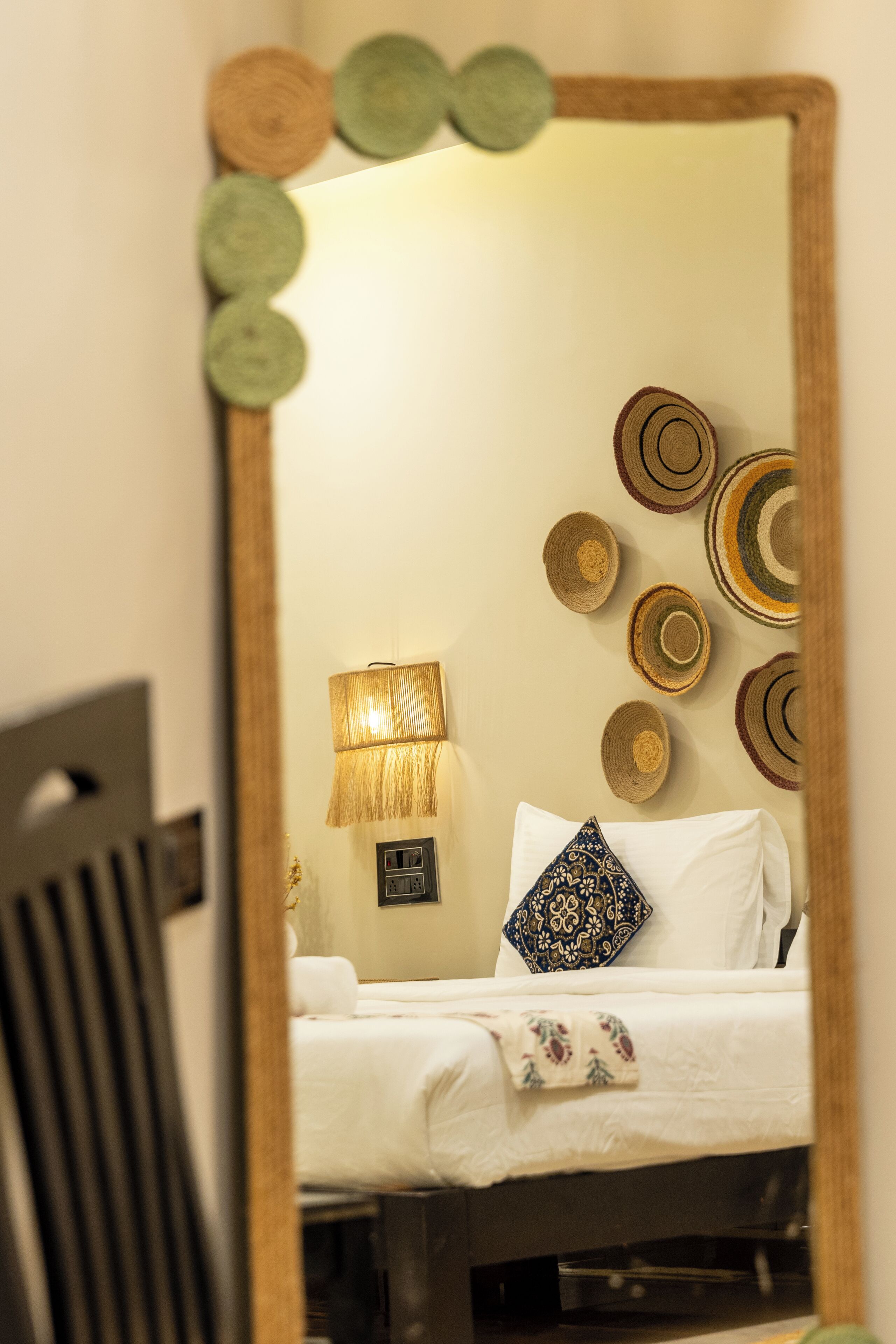 A hotel room with a bed, a lamp, and decorative wall hangings.