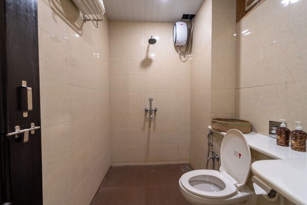 Une petite salle de bain compacte, équipée d’une douche, de toilettes et d’un lavabo.