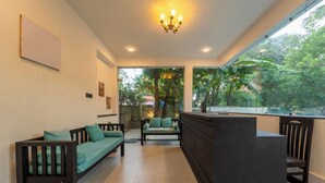 Ein modernes Interieur mit einer Rezeption, zwei hölzernen Sofas mit Kissen und einem großen Fenster mit Blick auf Grünflächen.