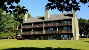 A multi-story building with a balcony on each floor, large windows, and a chimney.