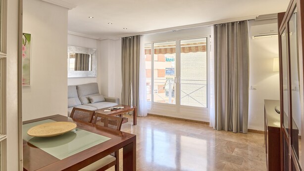 Amplia sala de estar con mesa de comedor, sofá y puerta corrediza de vidrio grande a un balcón.