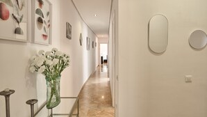 Un pasillo con obras de arte enmarcadas, un jarrón con flores y un espejo en la pared.