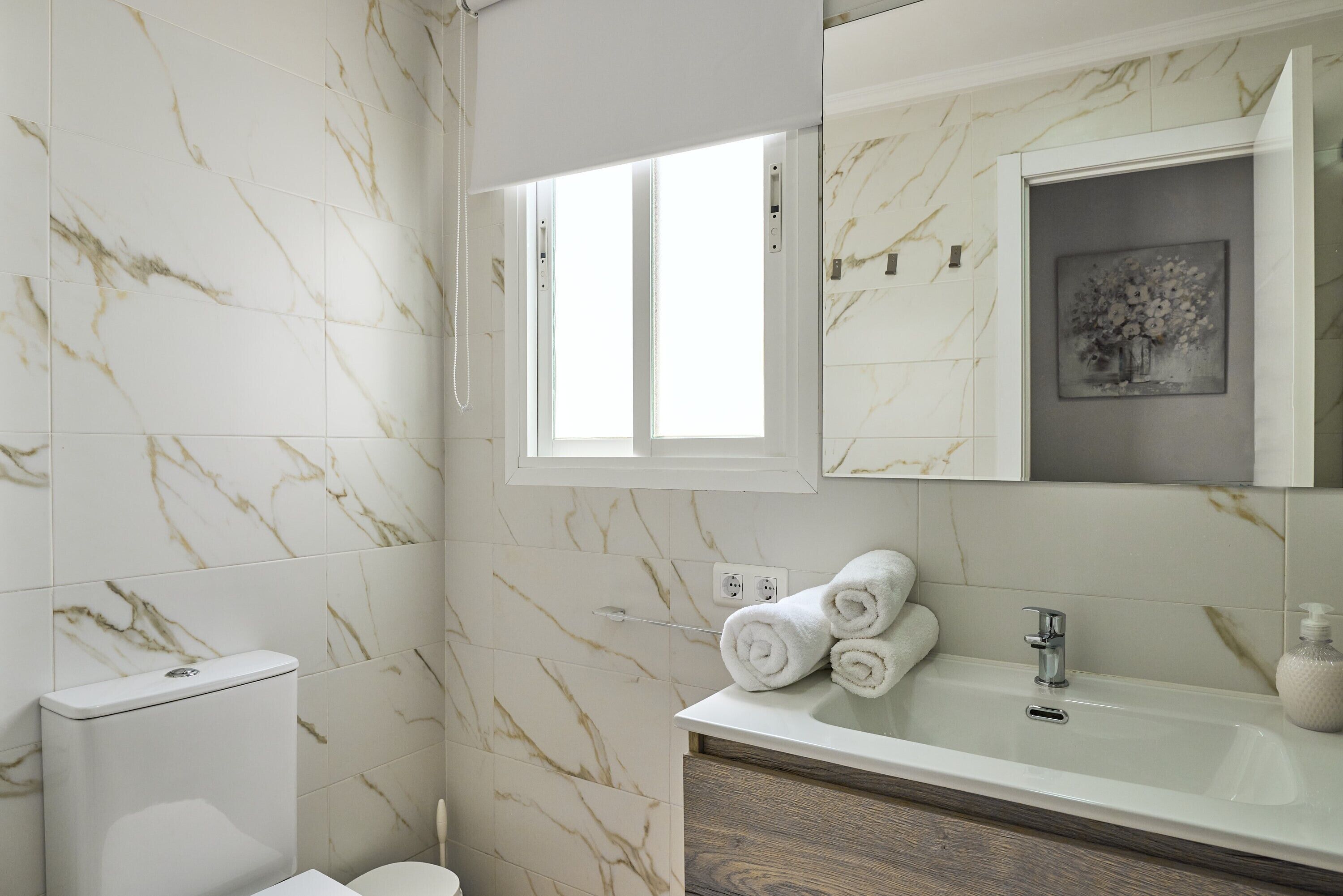 A bathroom with a toilet, sink, and a window.