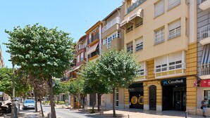 Una calle con edificios, árboles y un banco.