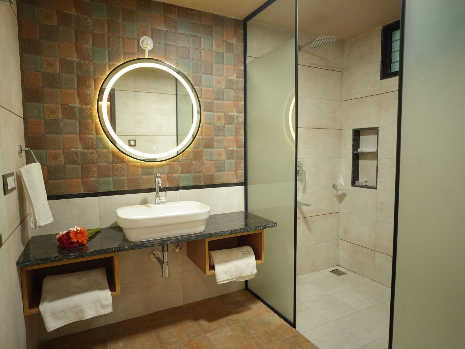 Une salle de bain moderne avec un miroir rond, un lavabo et un espace douche.
