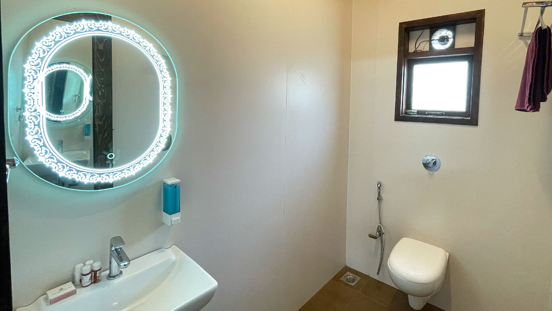 Un baño con espejo redondo, lavamanos, inodoro y ducha.
