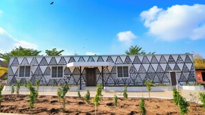A modern building with a geometric facade, multiple windows, and a central entrance. - Monteria Village  (Khalapur)
