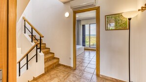 A staircase leading to a balcony with a view, a ceiling fan, and a framed artwork on the wall.