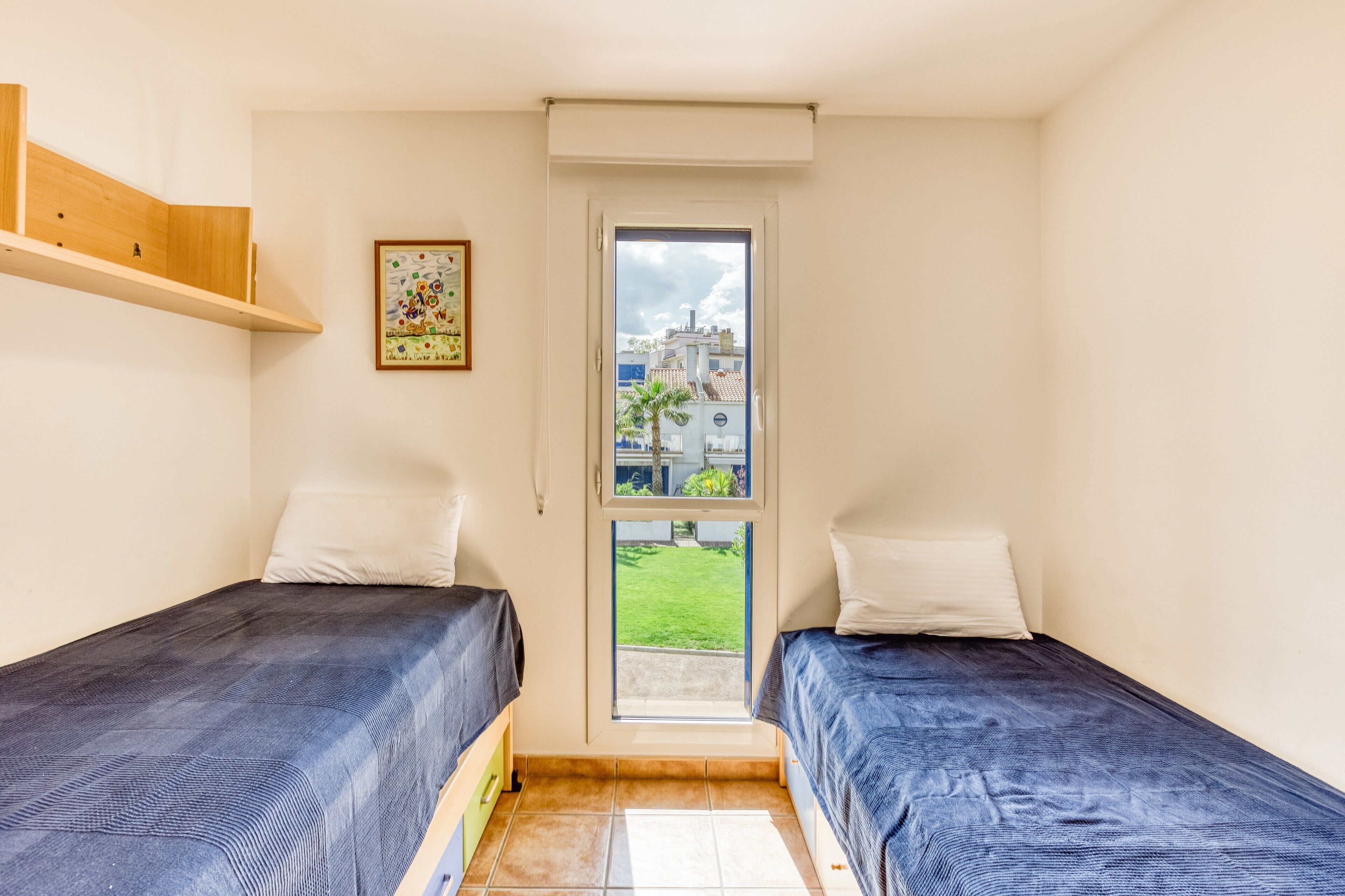 Una habitación pequeña y limpia con dos camas, una ventana y una puerta.