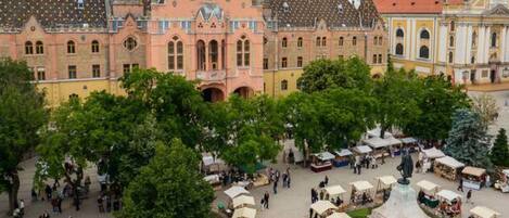 A historic building with a central courtyard, surrounded by trees and featuring a statue.