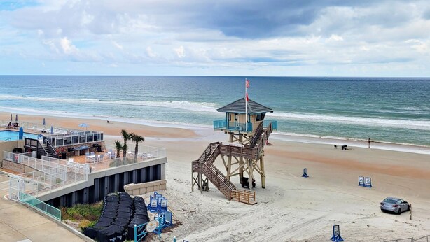 A beachside view with a lifeguard tower, a pool area, and a sandy beach.