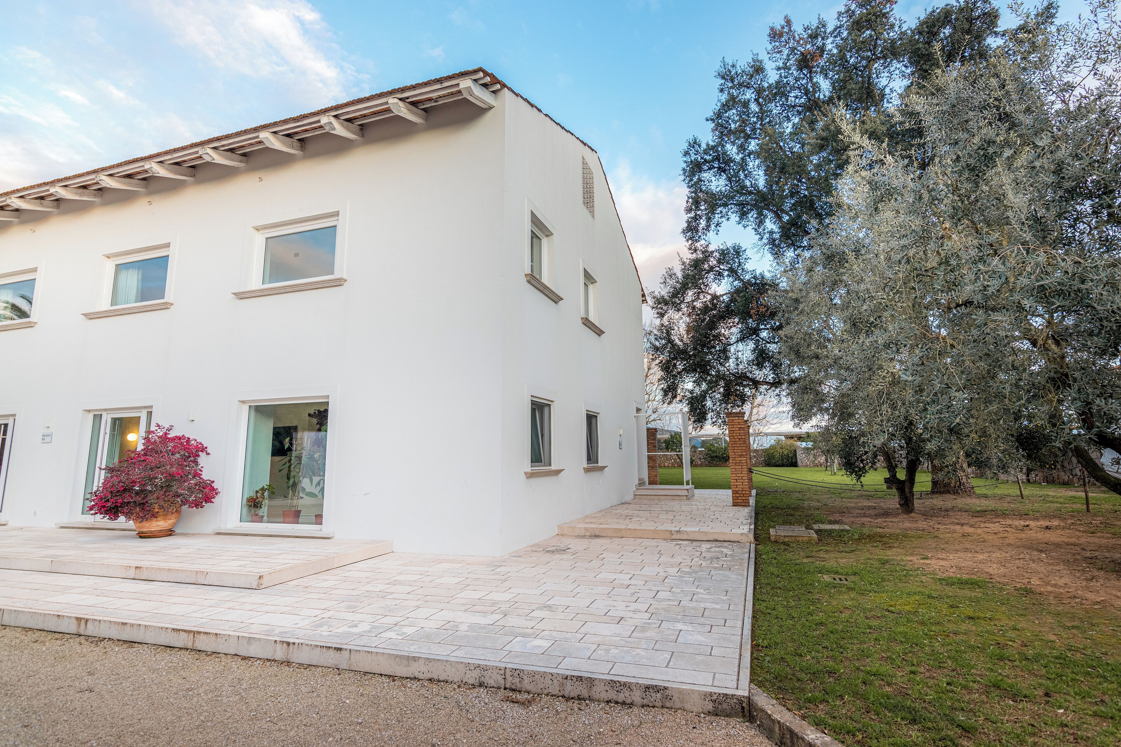 Un bâtiment blanc doté de nombreuses fenêtres et d’un espace d’entrée pavé.