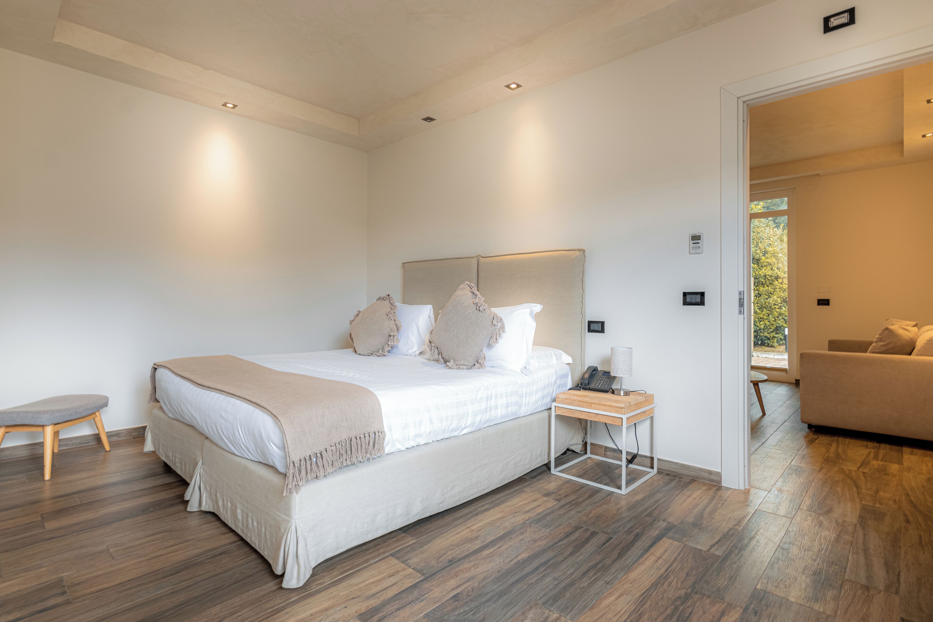 A modern bedroom with a large bed, bedside tables, and a view of a balcony.