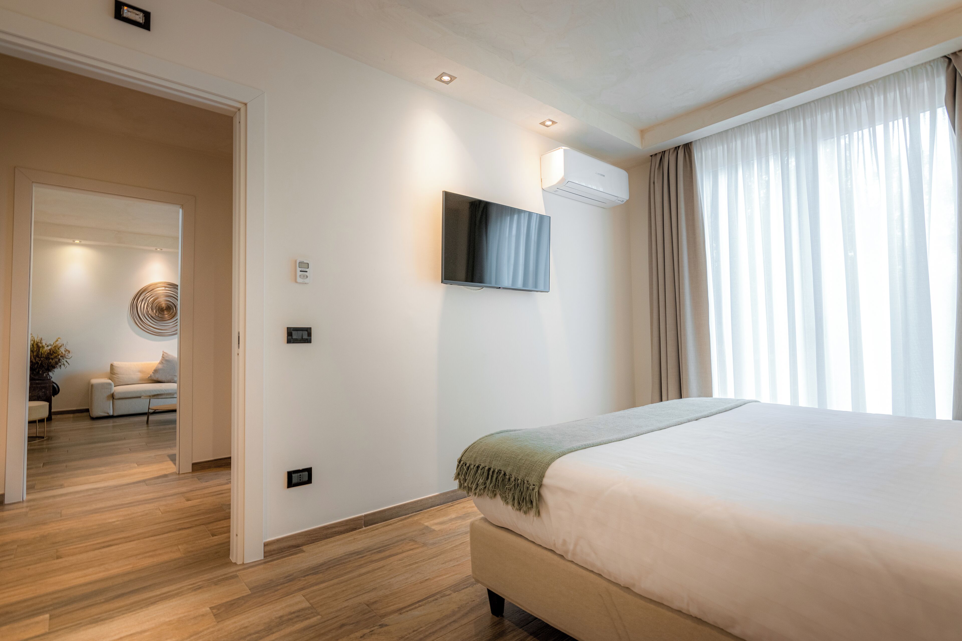 Une chambre d’hôtel moderne dotée d’un grand lit, d’un téléviseur à écran plat fixé au mur et d’un appareil de climatisation installé au plafond.