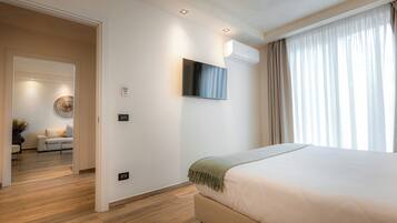 Une chambre d’hôtel moderne dotée d’un grand lit, d’un téléviseur à écran plat fixé au mur et d’un appareil de climatisation installé au plafond.