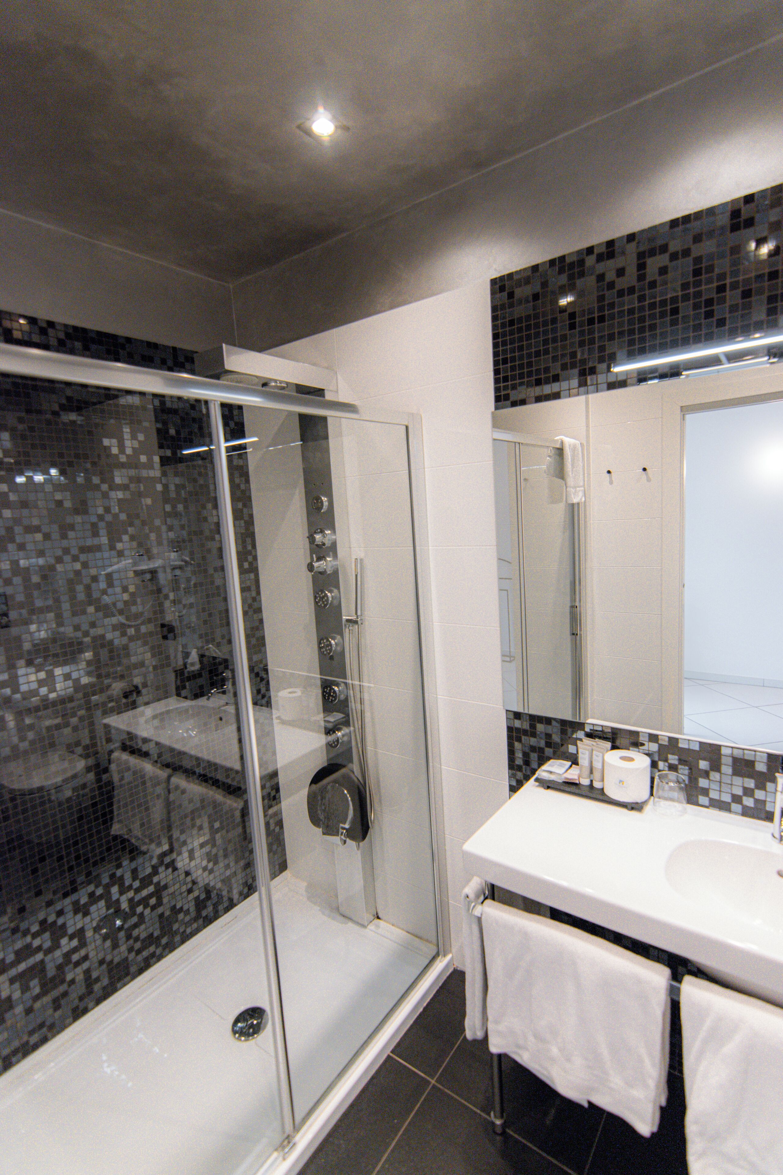 Un baño moderno con ducha de vidrio, lavamanos blanco y salpicadero de azulejos.