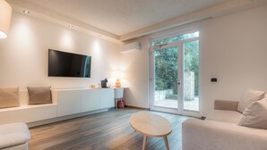 Een moderne woonkamer met een bank, een ronde tafel en een aan de muur bevestigde televisie.