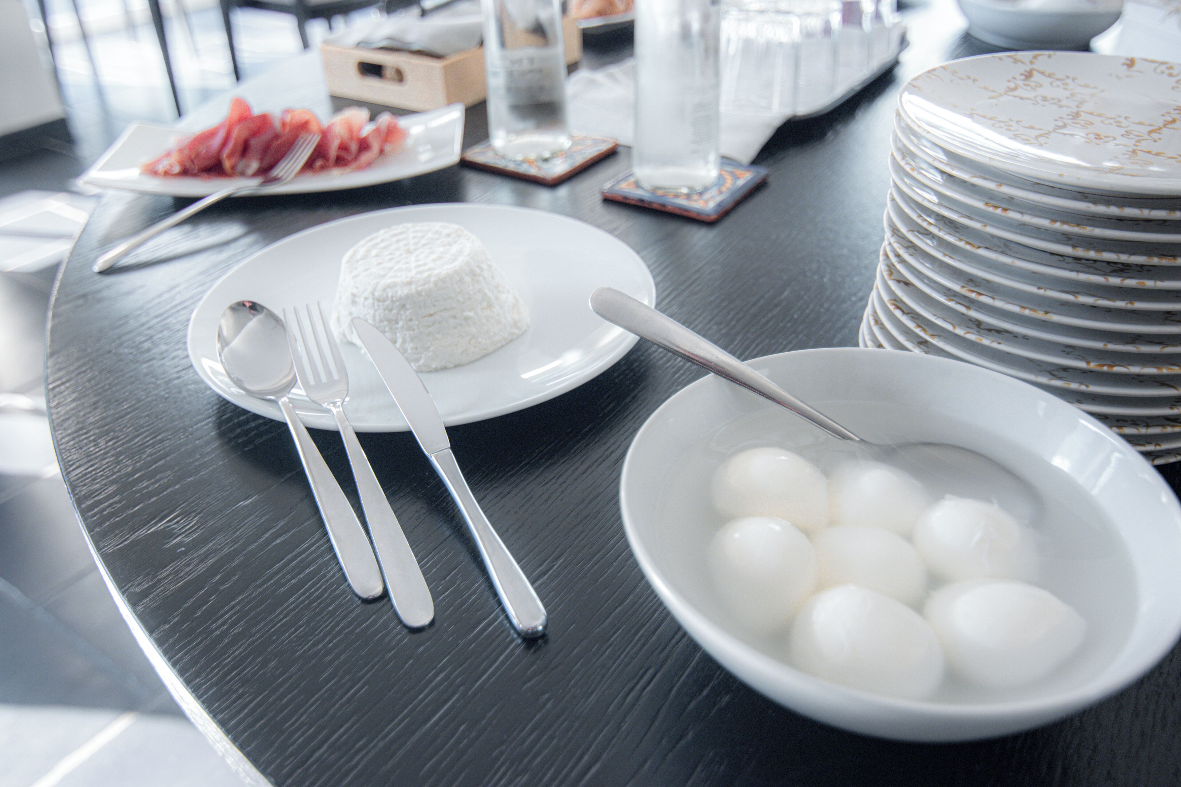 Une table à manger avec des assiettes, des couverts et un bol contenant des objets sphériques blancs.