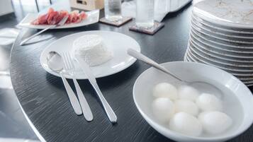 Une table à manger avec des assiettes, des couverts et un bol contenant des objets sphériques blancs.