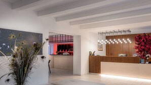 Een moderne hotel lobby met een receptiebalie, een zithoek en een keuken op de achtergrond.