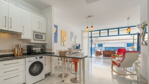 Une cuisine moderne équipée d’un lave-linge, d’un four à micro-ondes et d’un coin repas avec vue sur le salon.